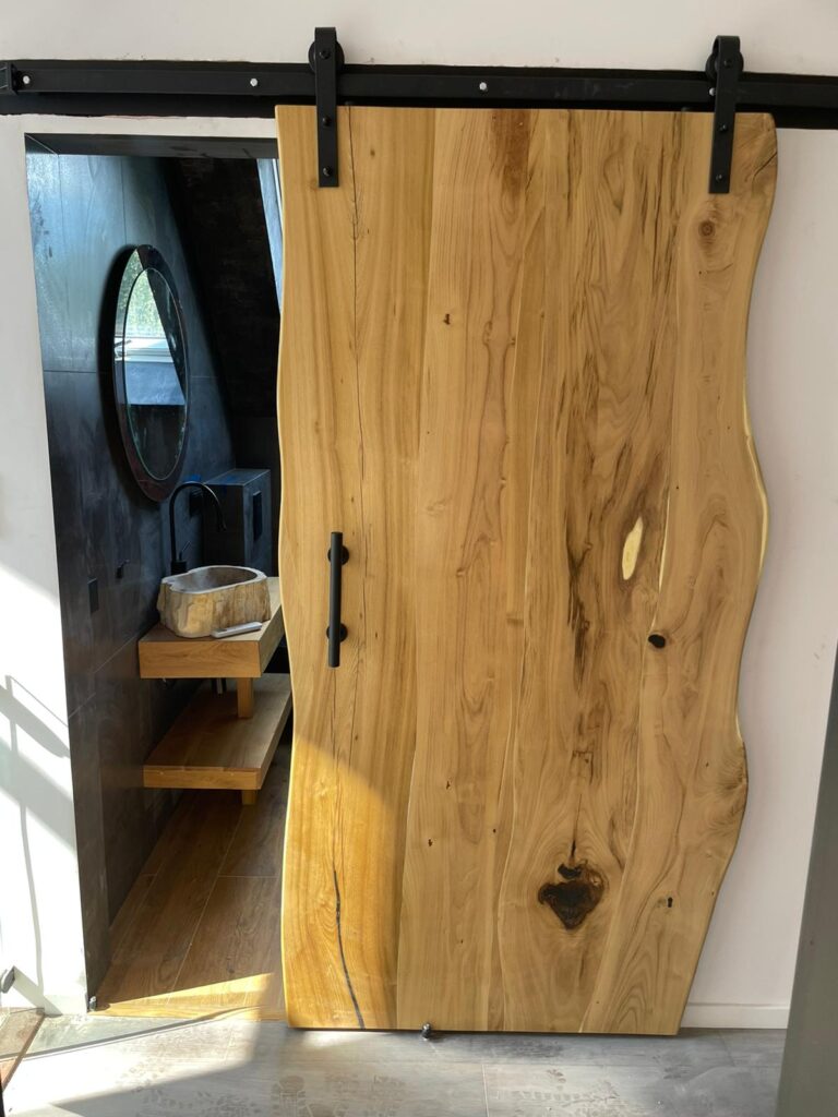 Prezentacja drewnianych drzwi przesuwnych z naturalną krawędzią w nowoczesnym wnętrzu.